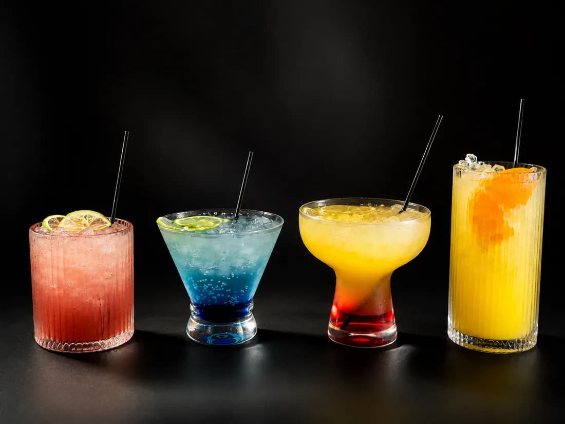 The four complimentary signature drinks at Sora Nail Bar — strawberry lemonade, the blue Ocean Drink, a Malibu Sunset and a mimosa — lined up on a black bar